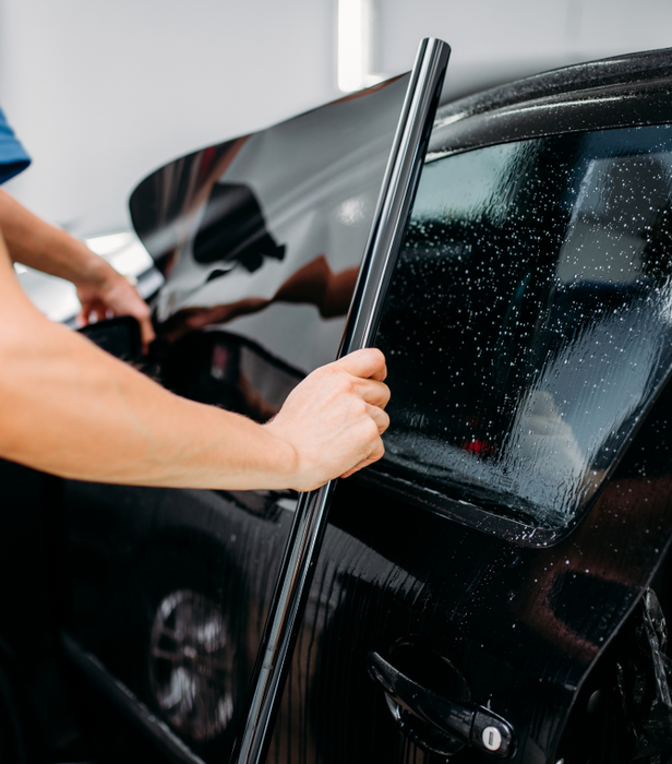 Genuscars technician installing window tint film on car side window